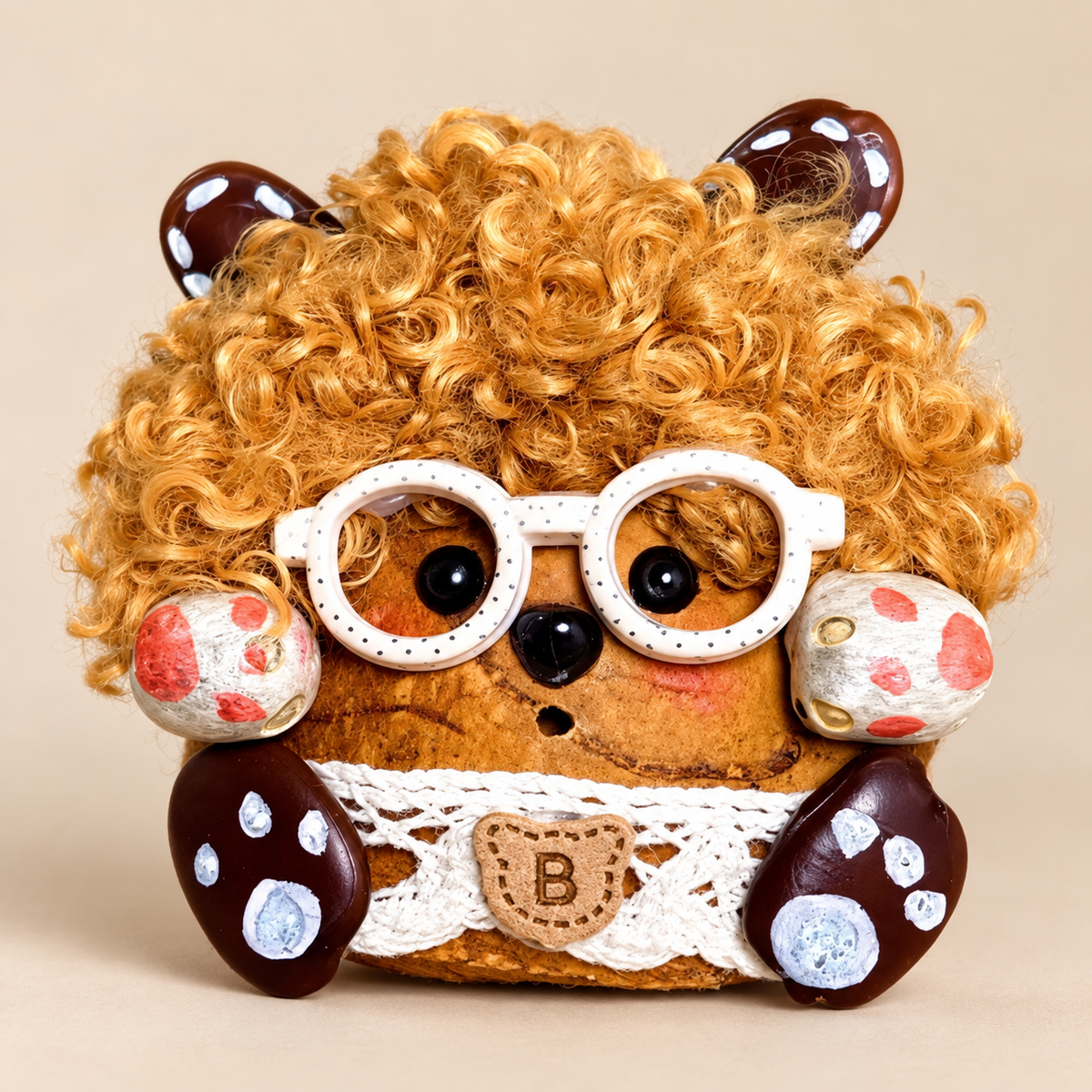 Front view of Curly, a Yunnan Keteng pod bag charm with golden curls and white round glasses