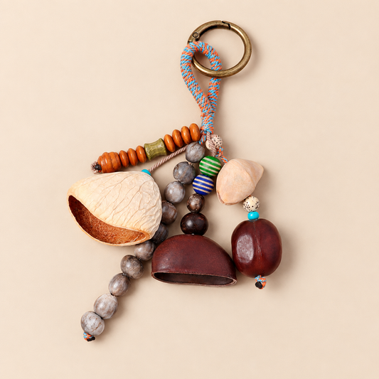 Handmade botanical shell bag charm with multicolored cord, clustered natural shells, and a brass-tone round clasp